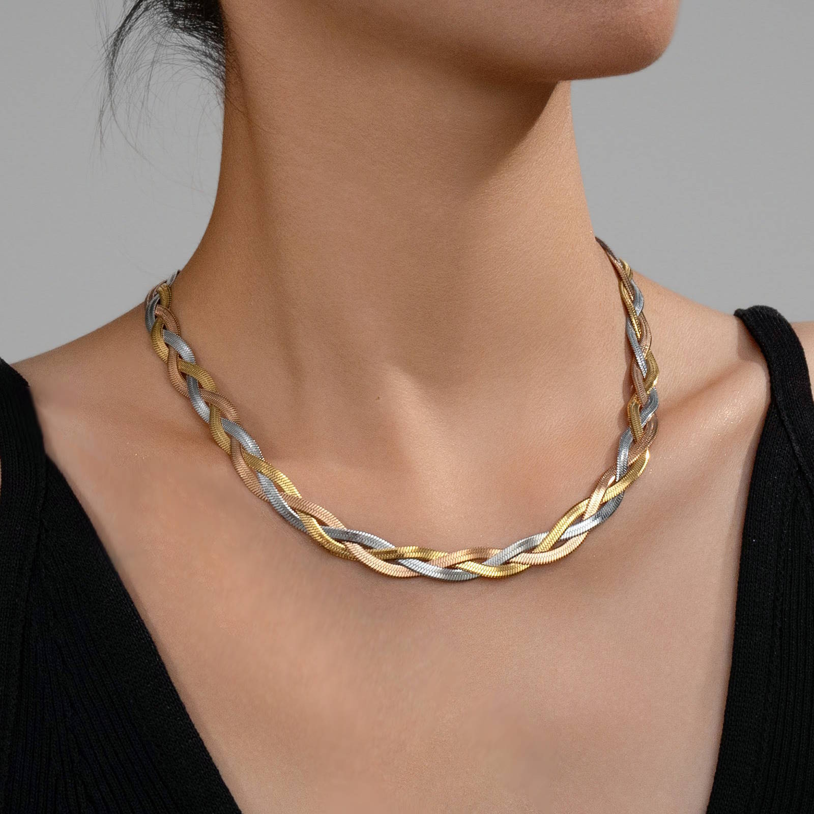 Tri-color braided necklace on a model against a gray background